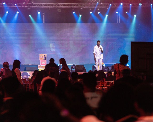 An audience watching the brightly lit comedy stage